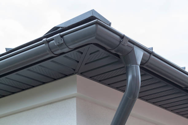 Corner of house with new gray metal tile roof and aluminum rain gutter. Metallic Guttering System, Guttering and Drainage Pipe Exterior