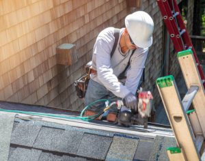 Roofing contractor using a nail gun to install shingles during a roof replacement in Northeast Florida