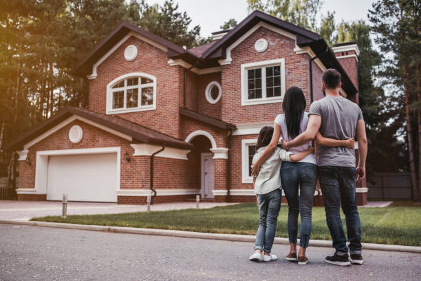 Back view of happy family is standing near their modern house and hugging