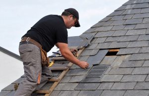 Roofing contractor laying shingles on sloped roof