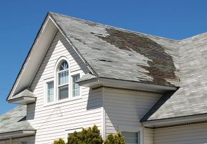 Storm-damaged roof with missing shingles and debris after severe weather