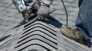 Prime Roofing contractor installing hip and ridge caps with a Hitachi roofing nail gun, essential roofing components for roof durability