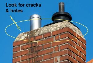Worn chimney crown on a residential roof with arrow pointing to signs of damage