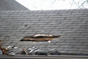 Shingles missing with visible hole in roof on residential home