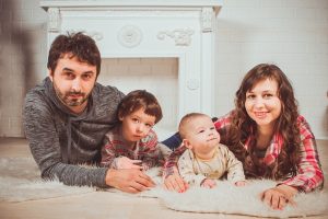 Happy young family of four smiling together at home
