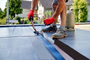 Roofing contractor installing modified bitumen, one of the common types of flat roofs