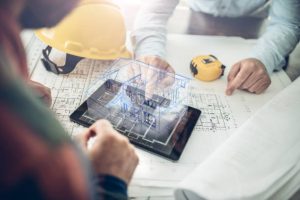 Builder and client reviewing house plans with latest roofing technology, projecting a virtual 3D home model on tablet