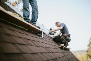 Roofing contractor safely installing shingles with proper safety gear on a suburban Florida home roof