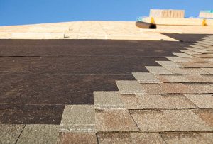 Roofers installing new shingles over old roof during a re-roofing project