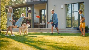 Happy family with golden retriever playing outside their energy-efficient home with a new roof