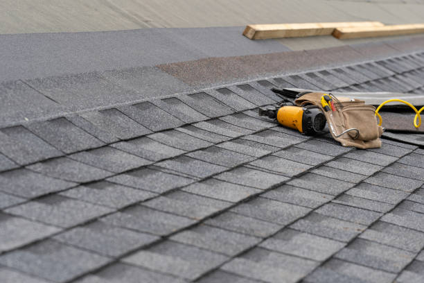 Toolbelt and nail gun on sloped asphalt shingle roof during essential roofing components installation