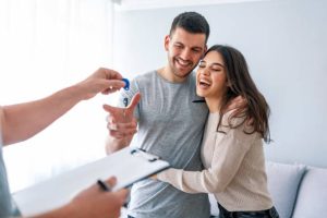 Young couple smiling and receiving house keys after hiring a trusted roofing contractor