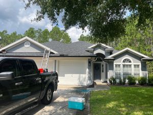 Tearing off old damaged shingles to inspect plywood roof deck during a residential roof replacement in St. Augustine.