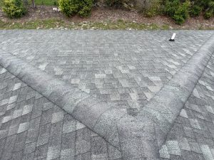Close-up shot of cracked pipe boot flashing and worn shingles around a roof vent penetration prior to replacement.
